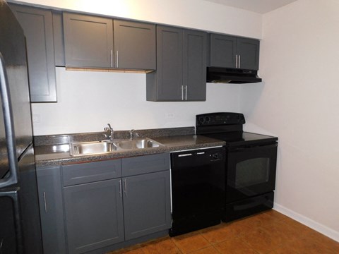 A kitchen with black cabinets and a black oven.