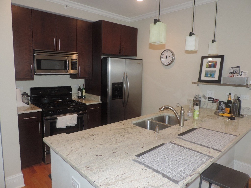 a kitchen with a marble counter top and a stainless steel refrigerator