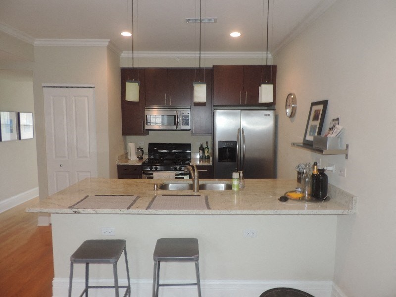 a kitchen with a bar and a stainless steel refrigerator