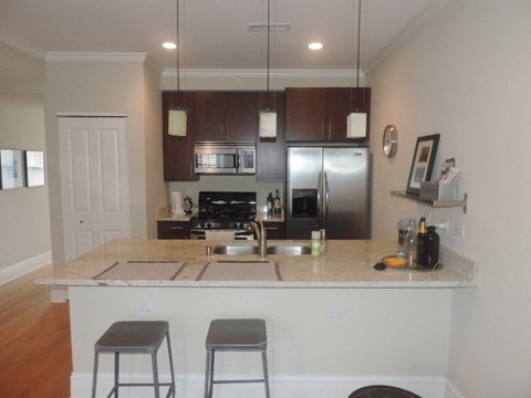 a kitchen with a bar and a stainless steel refrigerator