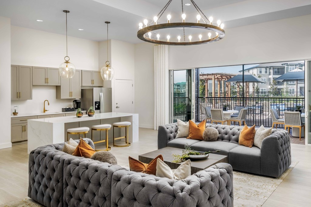 A modern living room with a grey tufted sofa and a chandelier.