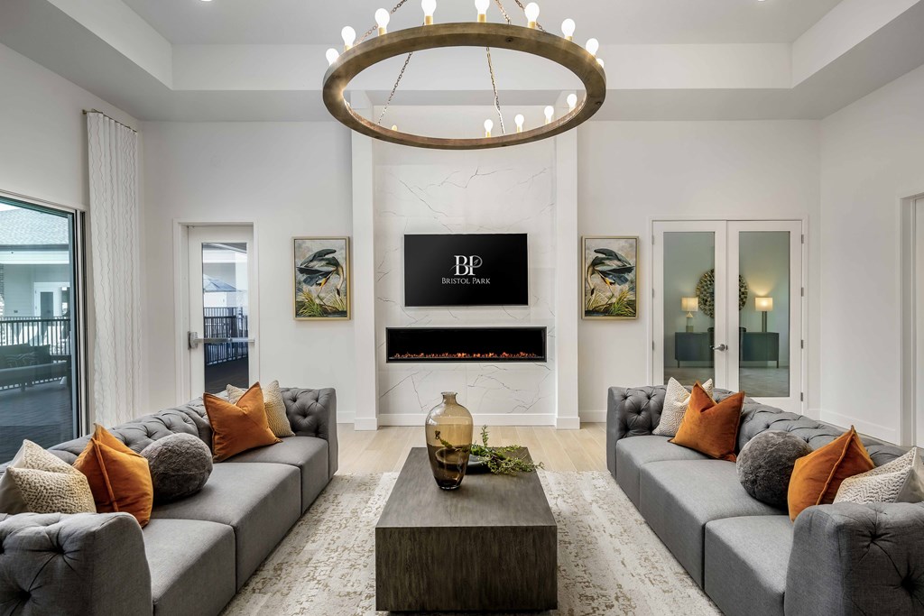 A modern living room with grey couches and a chandelier.