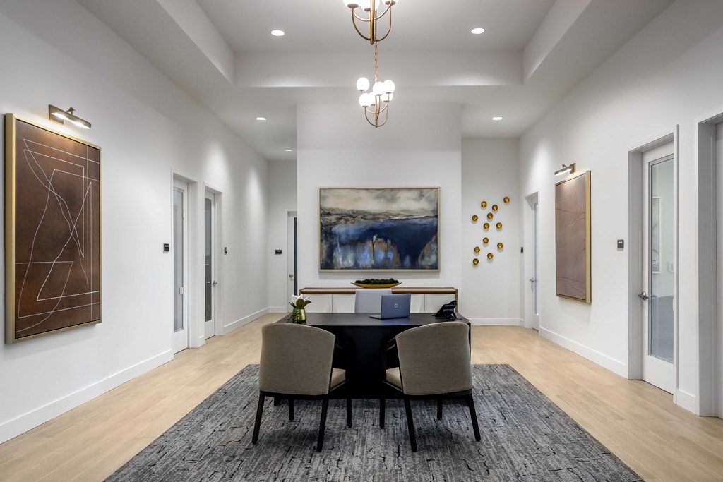 A dining room with a table set for two and a large painting on the wall.