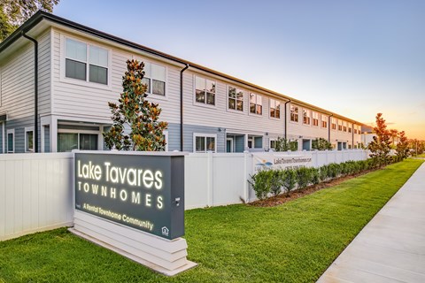 A sign for Lake Tavares Townhomes stands in front of a row of townhomes.