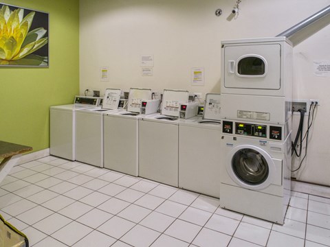 a row of washers and dryers in a laundry room with washing machines