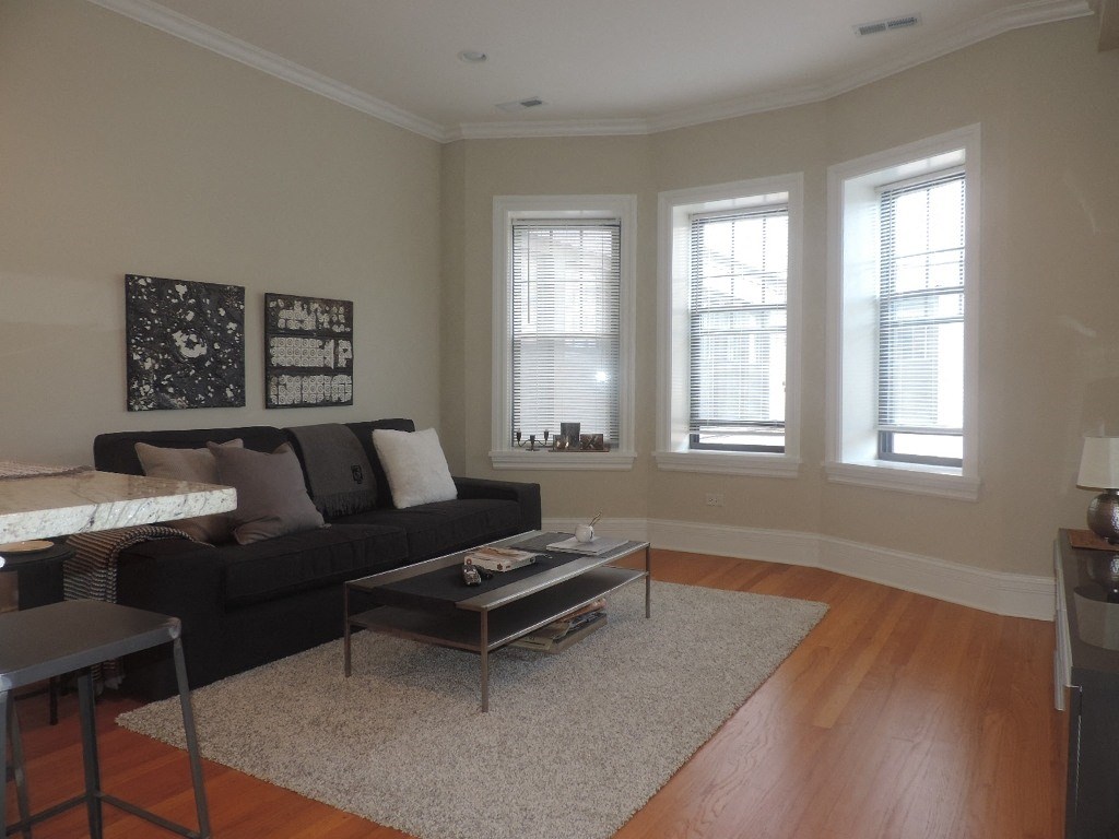 a living room with a couch and a table and three windows