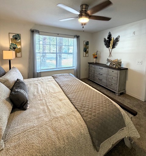 A bedroom with a large bed and a ceiling fan.