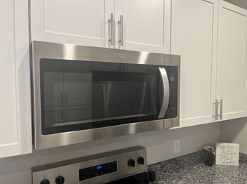 A stainless steel microwave oven with a digital control panel is installed above a stove.