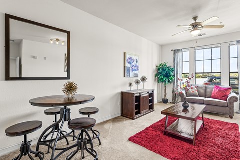 A living room with a round table and a red rug.