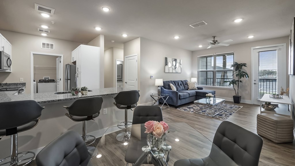 A modern kitchen with a bar area and a living room with a couch.