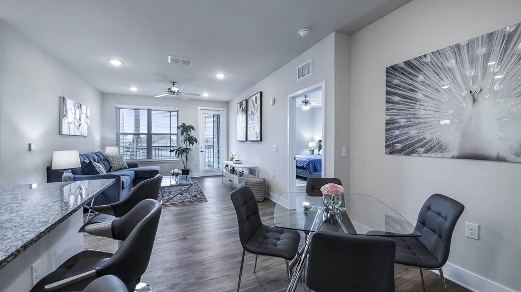 A modern living room with a glass dining table and black chairs.