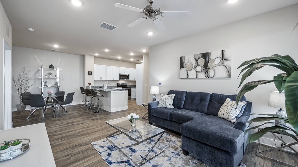 A modern living room with a grey sofa and a dining area in the background.