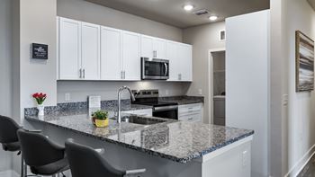 A kitchen with granite countertops and white cabinets.