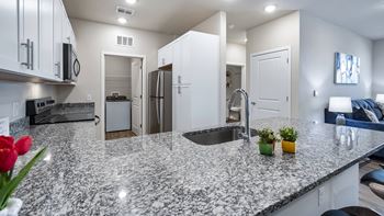 A kitchen with granite countertops and white cabinets.