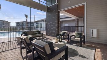 A patio with a table and chairs overlooking a pool.
