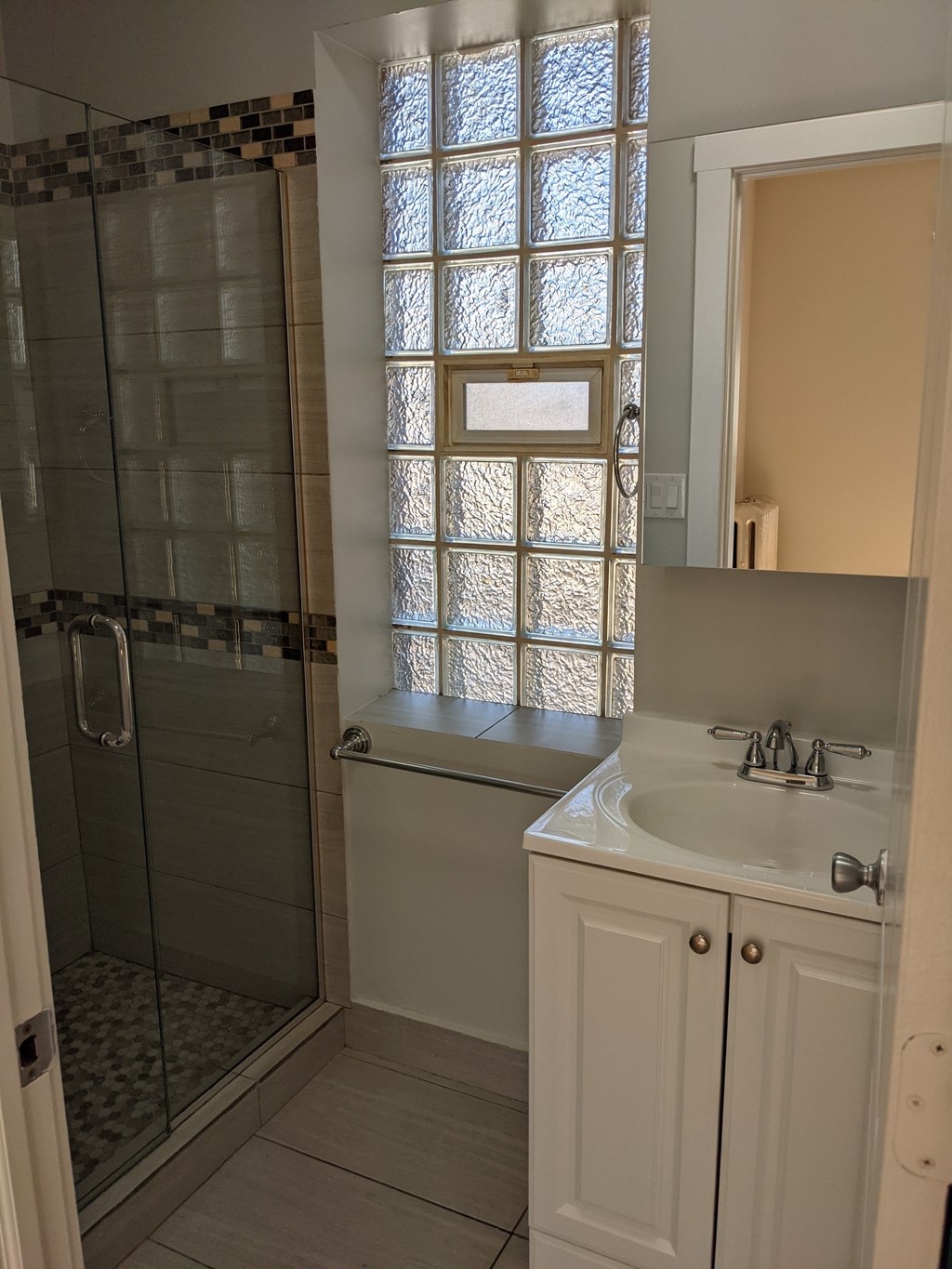 A bathroom with a white sink and a shower with a glass door.