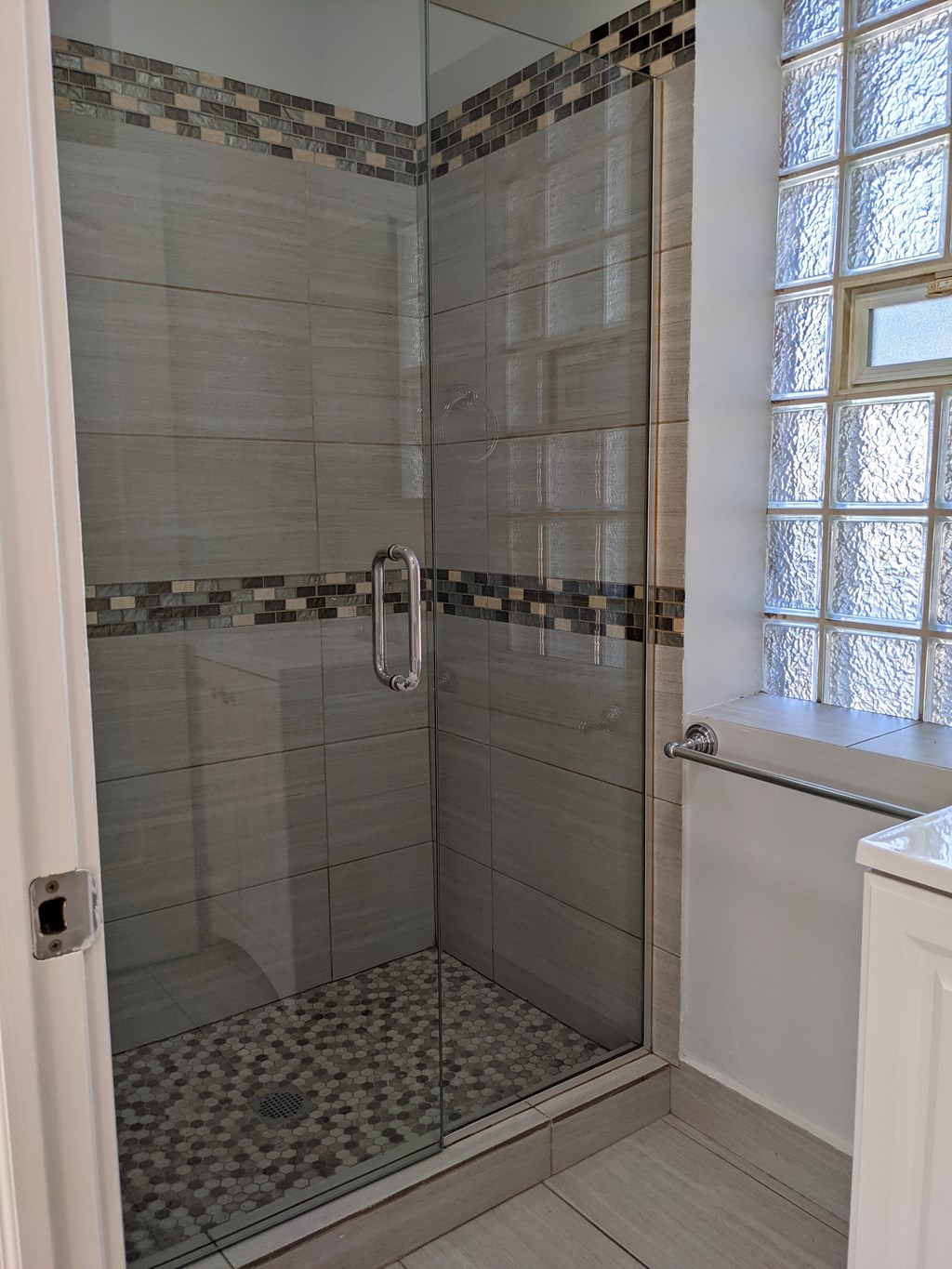 A shower with a glass door and a tiled floor.