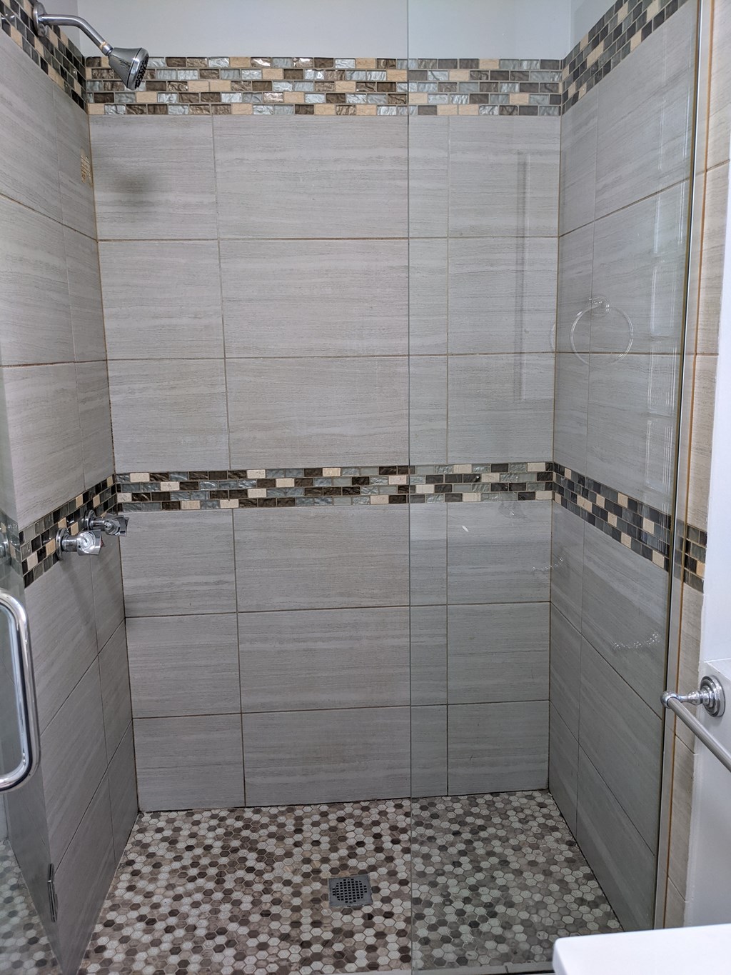 A shower area with a tiled floor and walls.