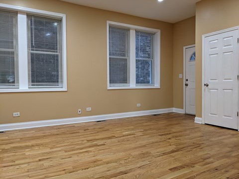 A room with wooden floors and two windows.