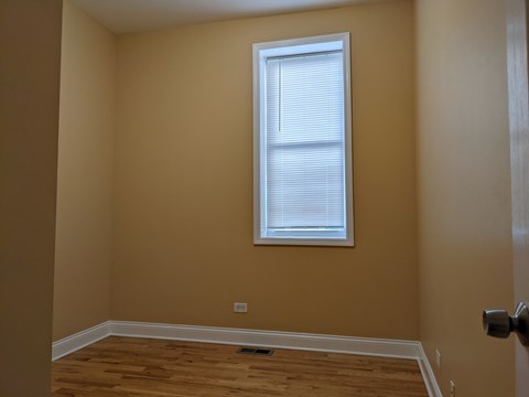 A room with a window and wooden flooring.