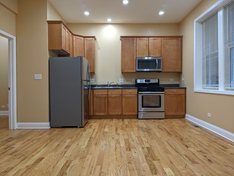 A kitchen with wooden floors and a refrigerator.