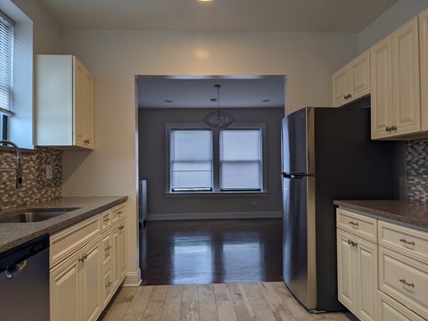 A kitchen with a black refrigerator and white cabinets.