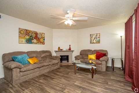 A living room with a brown couch, a fireplace, and a painting on the wall.