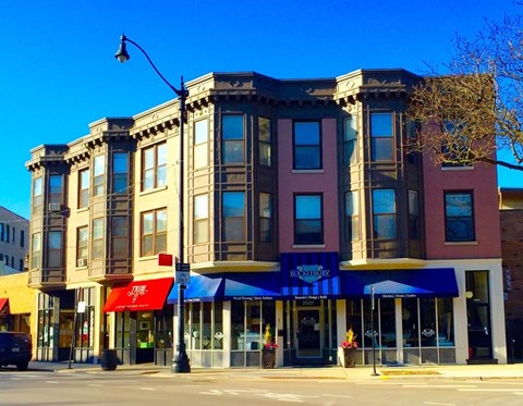 A row of three buildings with the middle one having a blue awning.