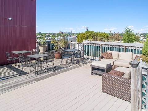 a deck with a couch and tables on a roof