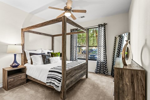 A bedroom with a four poster bed and a ceiling fan.