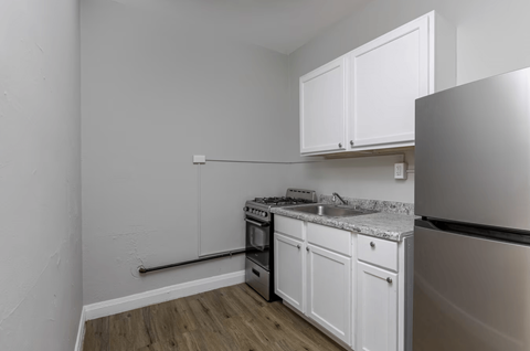 A kitchen with white cabinets and a stainless steel refrigerator.