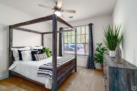 A bedroom with a four poster bed and a ceiling fan.