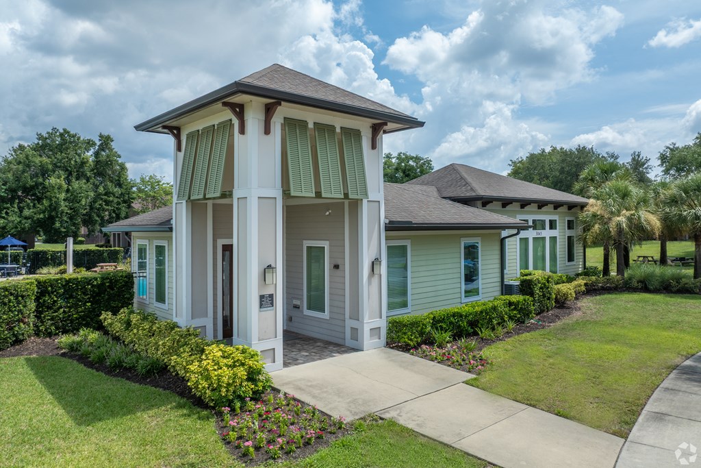 A house with a white and green exterior and a brown roof.
