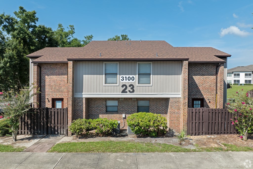 A house numbered 23100 is shown with a brown fence and green bushes.
