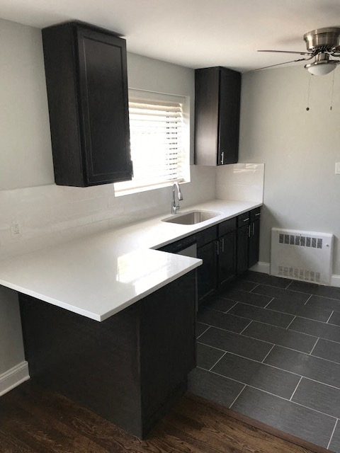 A kitchen with black cabinets and a white countertop.