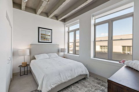 A bedroom with a large bed and a window overlooking a building.