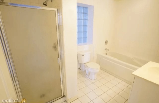 a white bathroom with a toilet and a shower