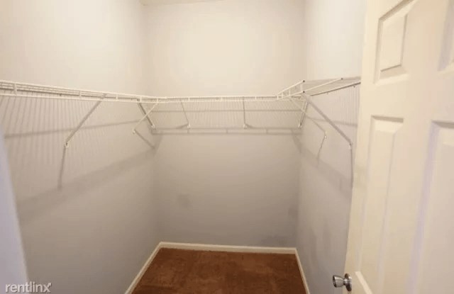 a white walk in closet with white shelves and a door