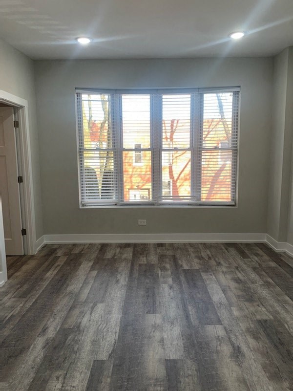 an empty living room with a window and wood floors