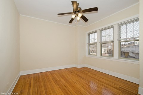 an empty room with a ceiling fan and three windows