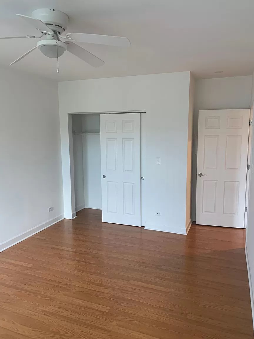 an empty living room with wood floors and a ceiling fan