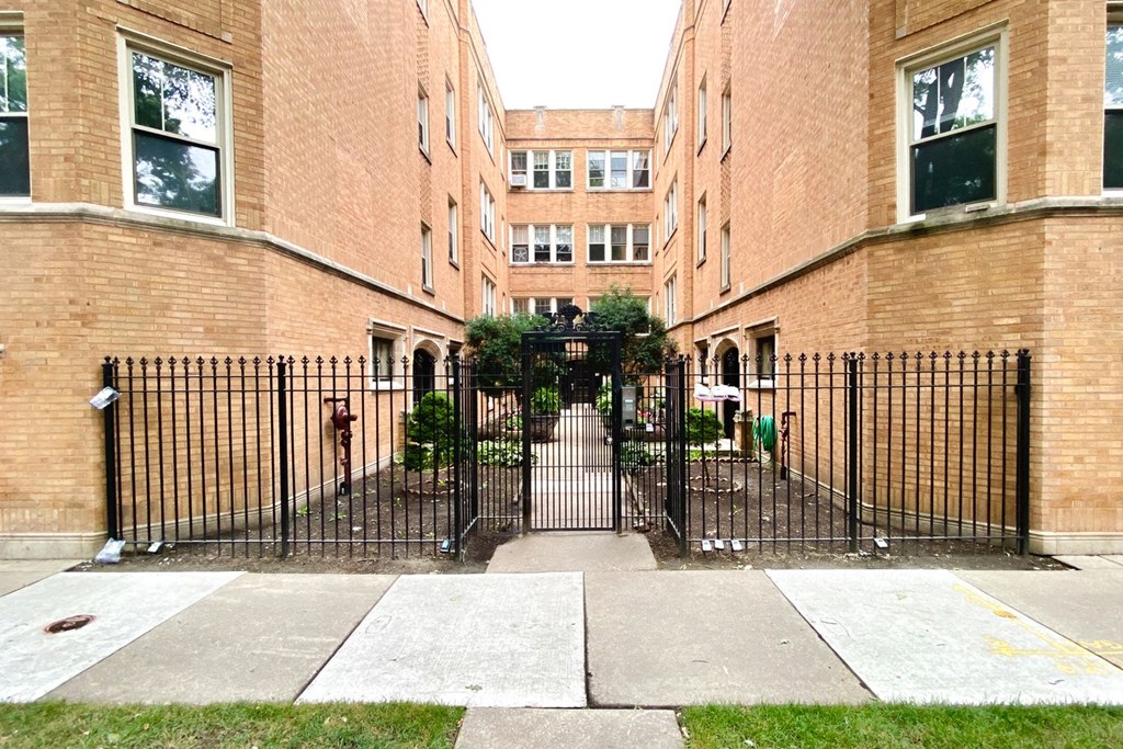 a courtyard between two brick buildings with a wrought iron gate