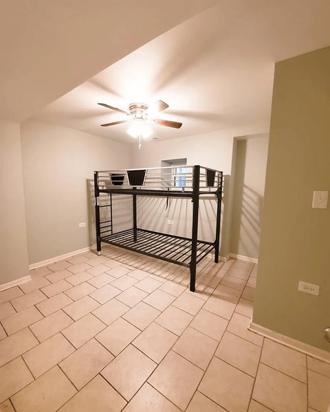 A room with a ceiling fan and a shelf.