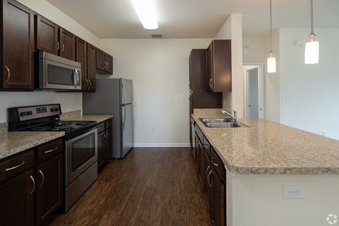 A kitchen with dark brown cabinets and a granite countertop.