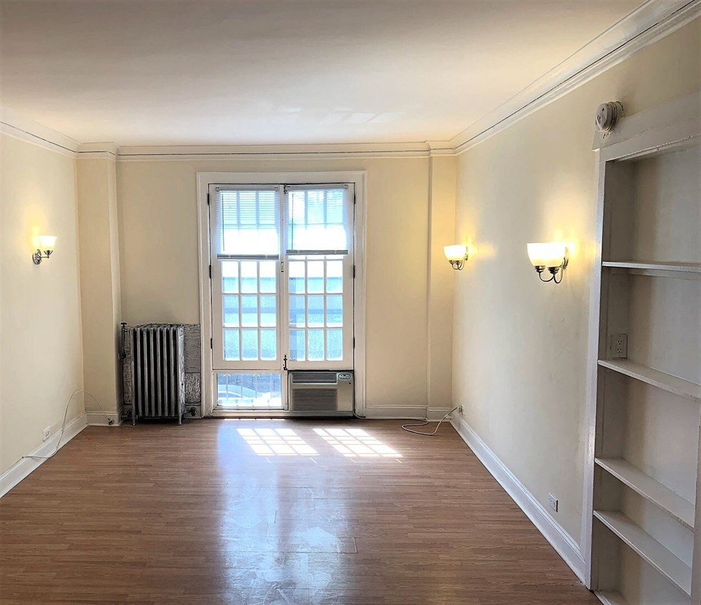 an empty living room with a window and wooden floors