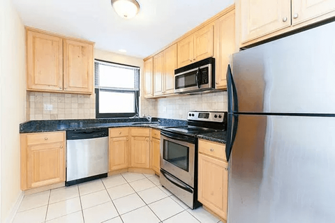 A kitchen with wooden cabinets and black countertops.