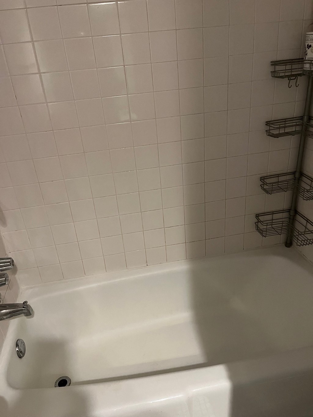 a white bath tub in a white tiled bathroom