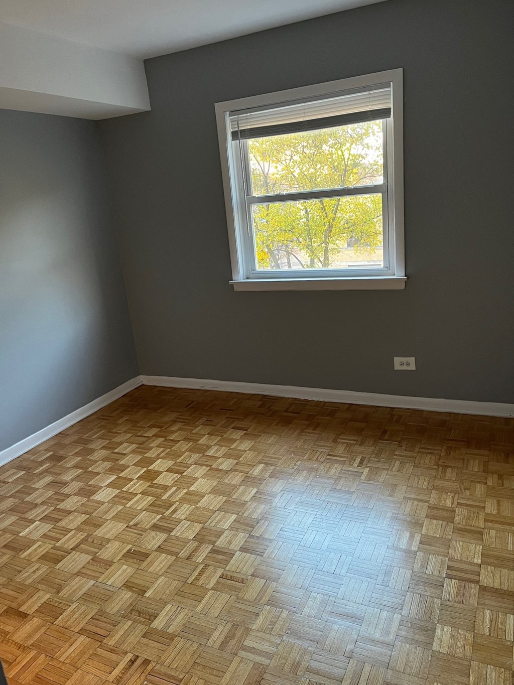 an empty room with a window and wooden floors