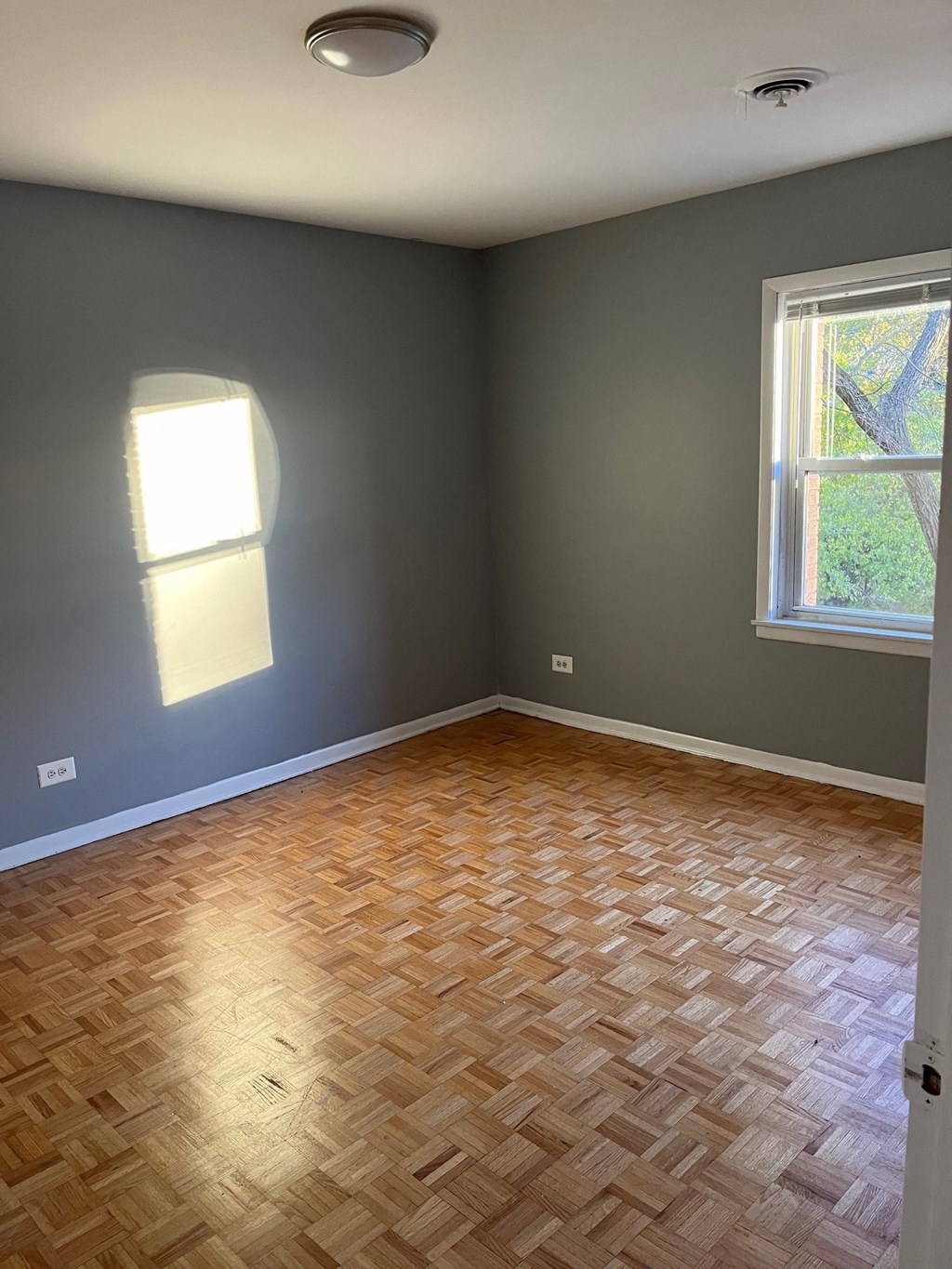 an empty room with wood flooring and a window
