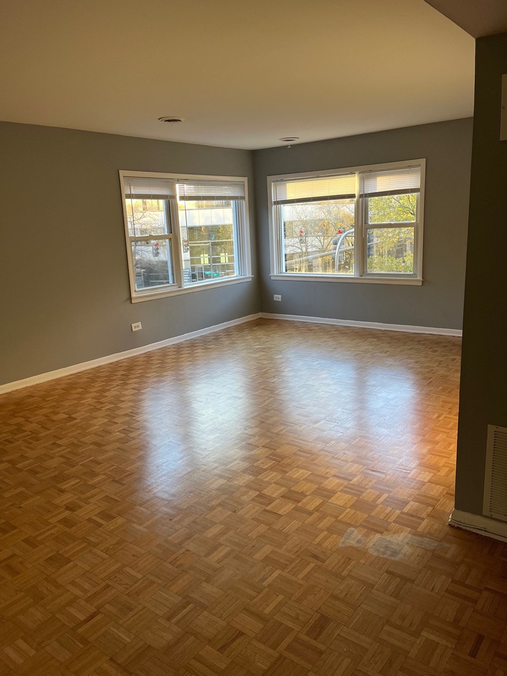 an empty living room with wood flooring and three windows